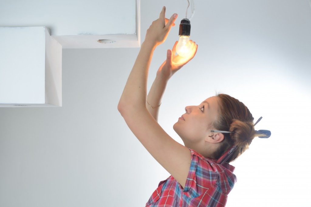 girl replacing light bulb