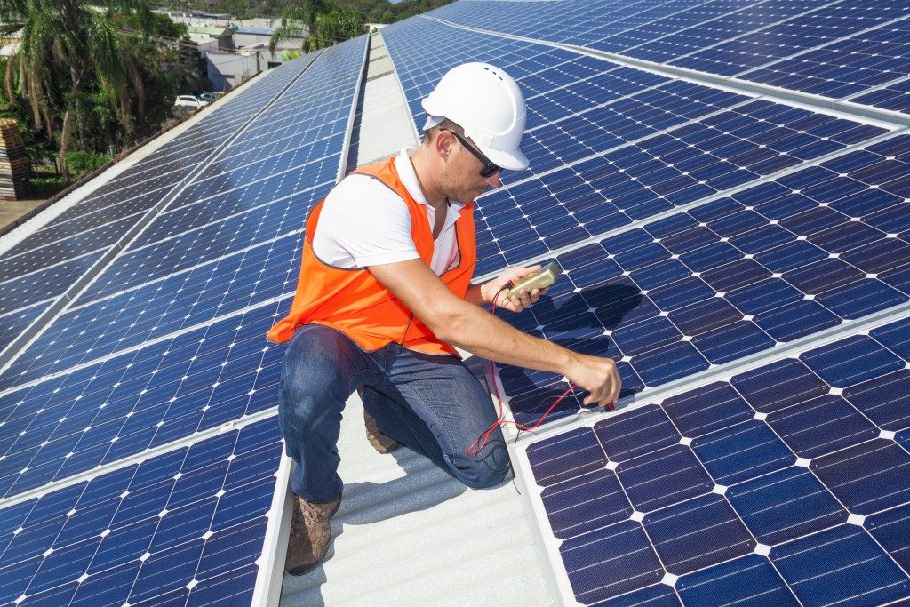 technician checking solar panels on factory roof