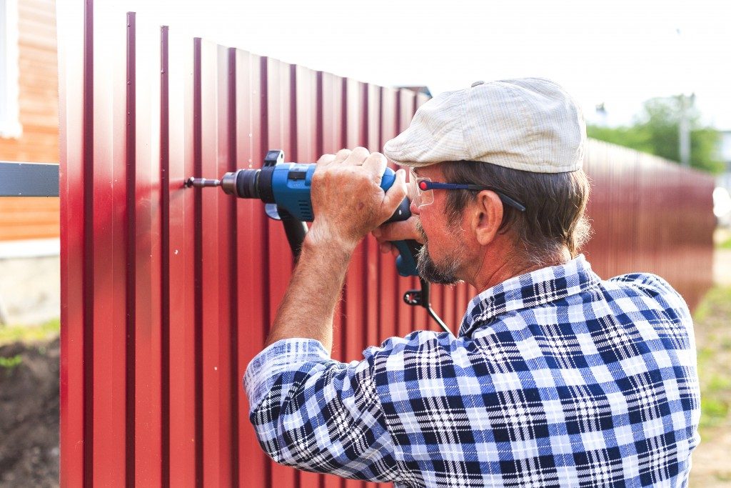 man placing a fence around his home