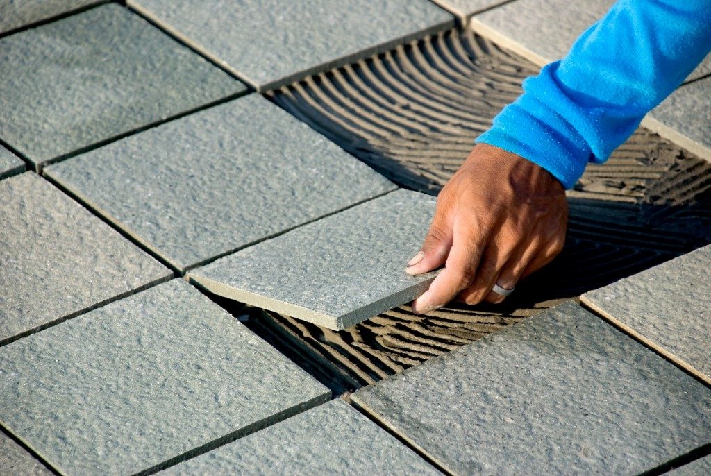 close up of a hand installing a floor tile