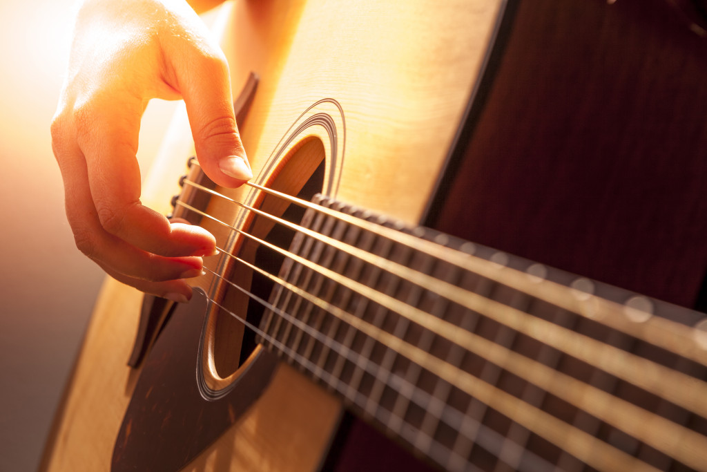 woman's hands playing acoustic guitar, close up