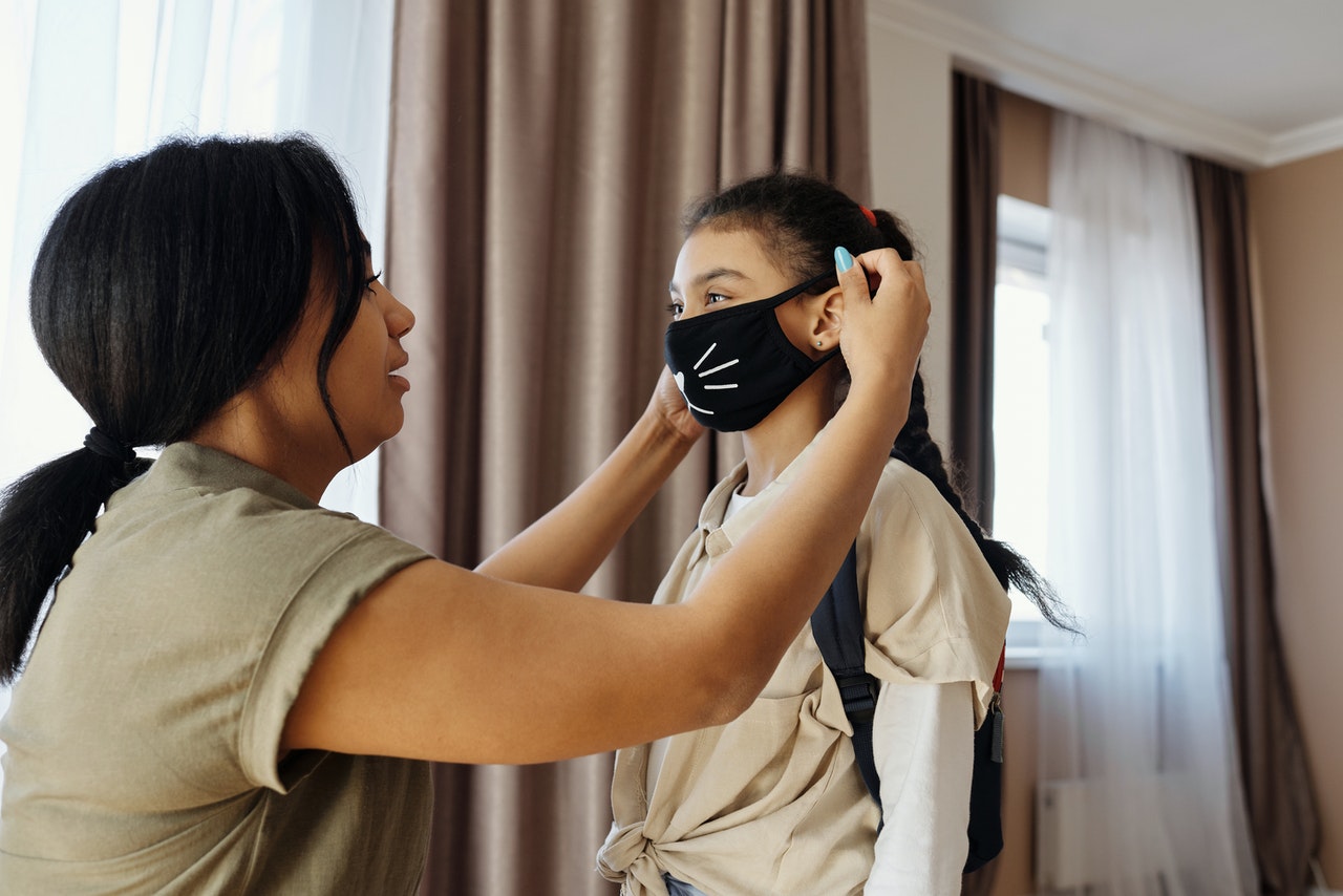 mom putting her daughter's mask on