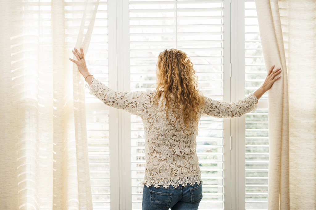 woman opening the curtains