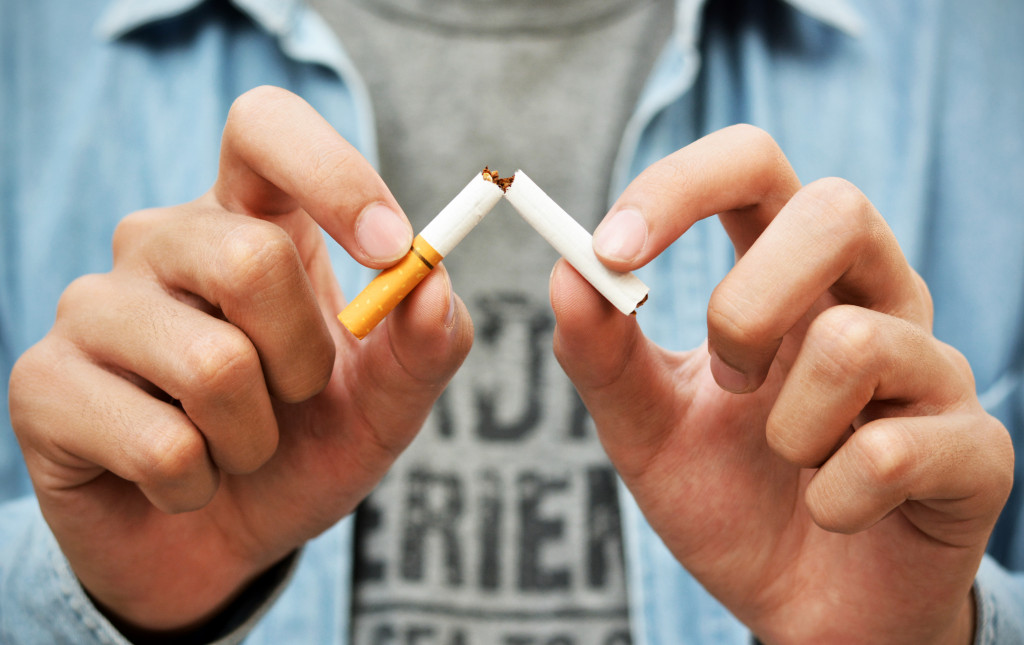 man breaking a cigarette into two pieces