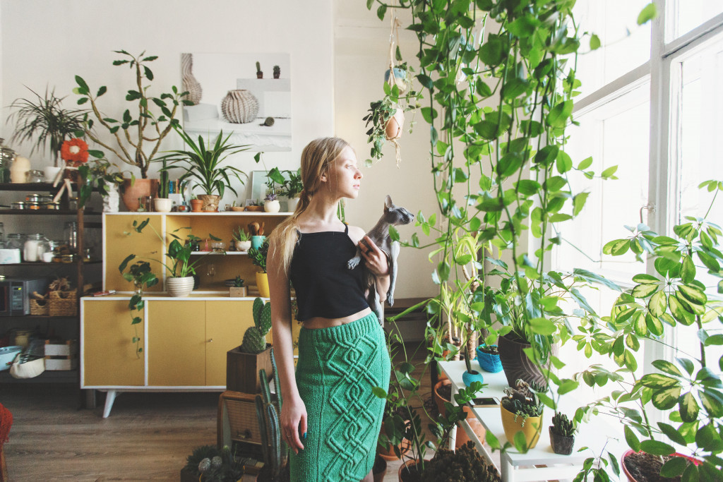 woman holding cat with plants indoors