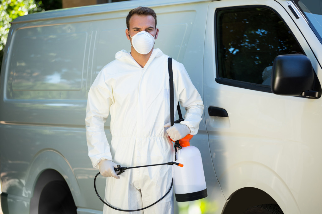 A man standing in front of white van with pest control spray 