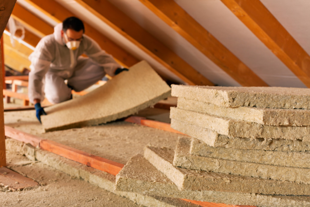 A man installing thermal insulation under the roof