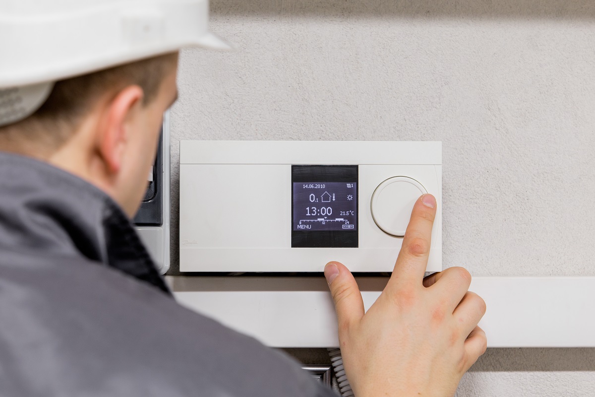 HVAC professional testing the thermostat on the wall